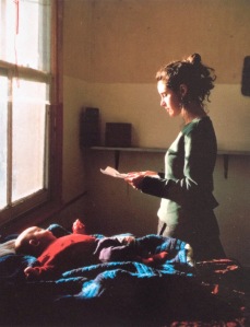 Young woman reading a letter with a baby on the bed Tom Hunter(born 1965)